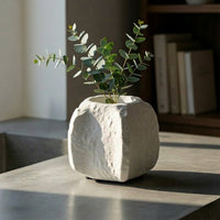 White textured decorative flower vase placed on table with green leaves modern minimal home decor styling idea.