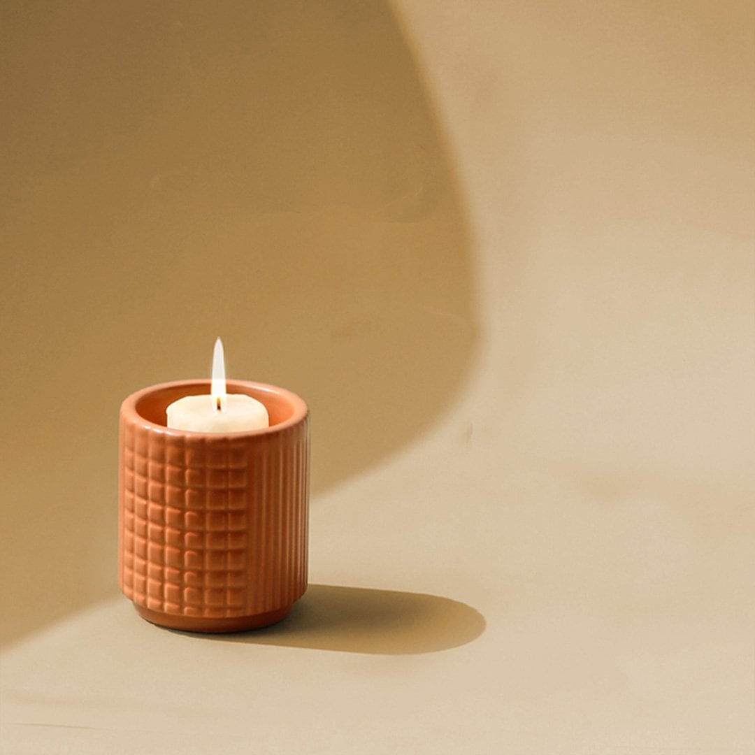 Textured terracotta candle holder placed on a soft white background ideal for modern shelves tables and warm cozy decor.