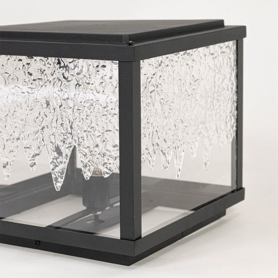 Closeup of outdoor lantern light highlighting black metal frame textured glass panels and durable contemporary exterior design.