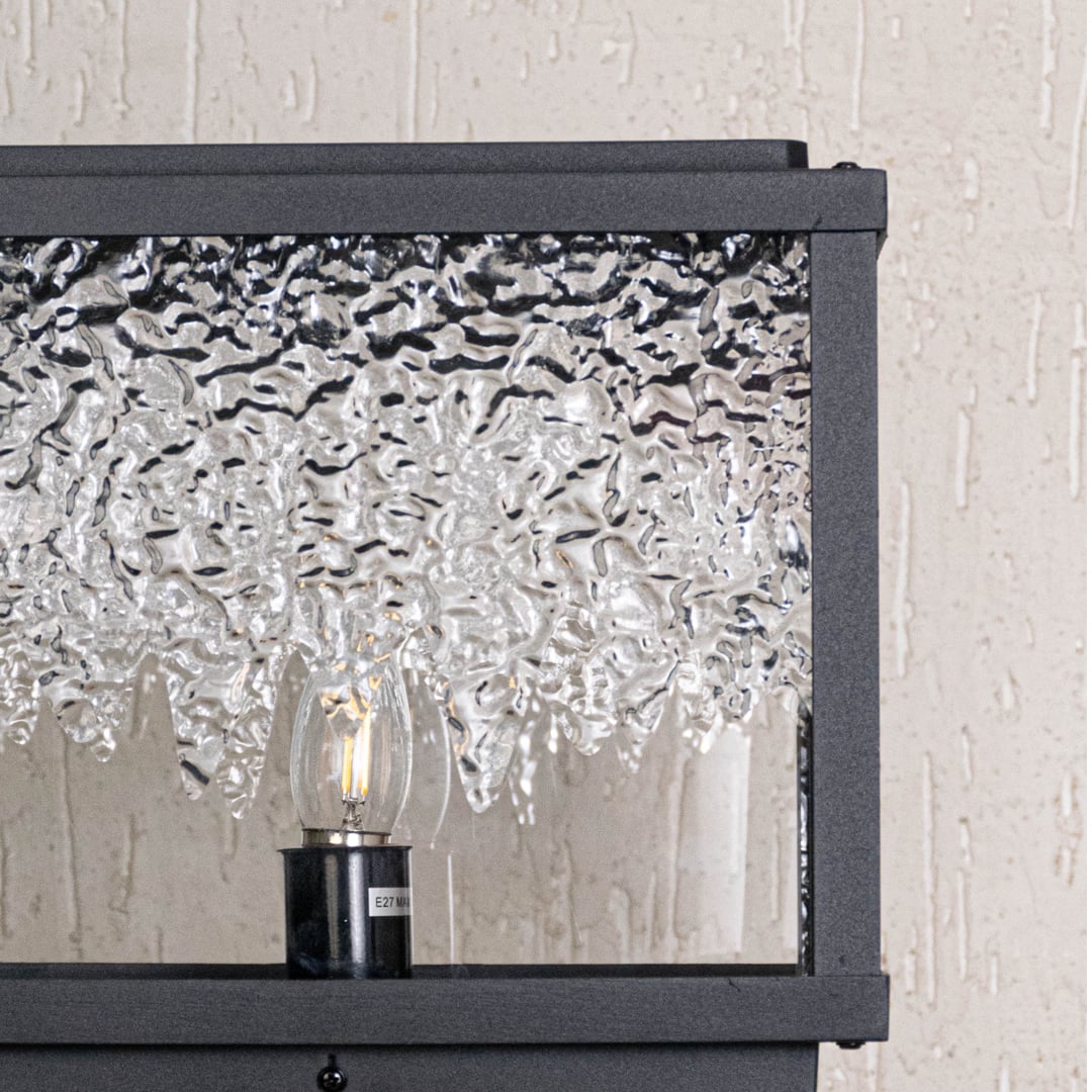 Close view highlighting smooth textured glass pattern and fine black metal structure of designer pillar light.