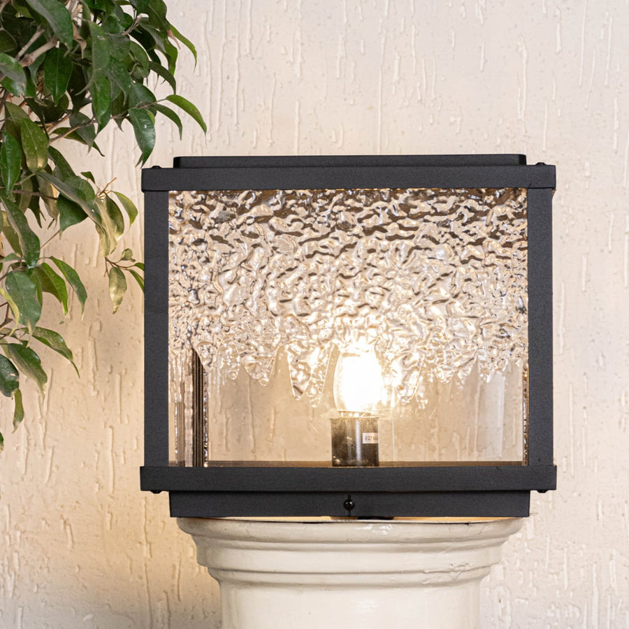Outdoor wall light in black metal with textured glass shade displayed on white background highlighting classic exterior lighting design.