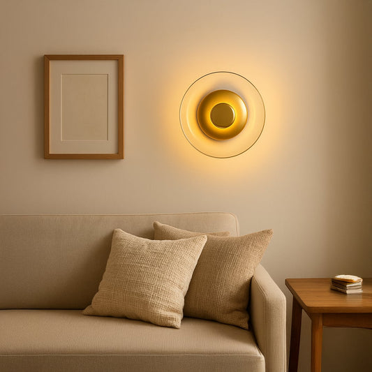 Round gold wall light with glass shade illuminating a modern living room adding elegance and soft ambient glow.