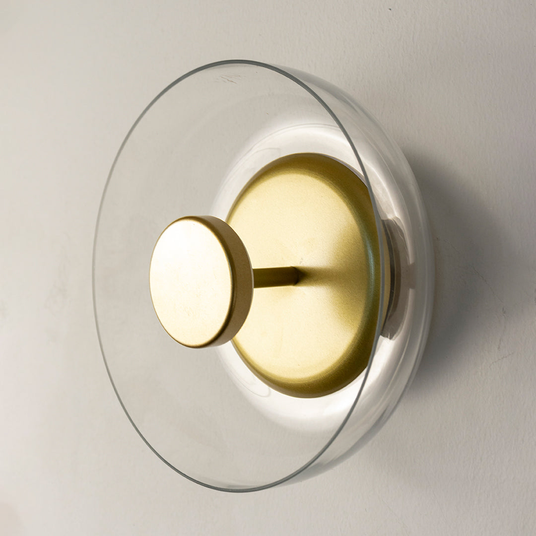 Modern gold metal wall light with clear glass shade for luxury bedroom hallway and contemporary home decor spaces.