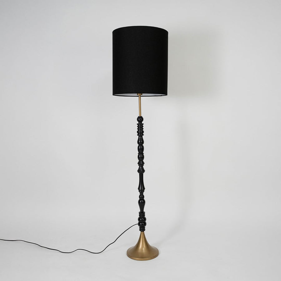 Black fabric shade floor lamp with sculpted wood stem and brass base for sophisticated interior lighting and decor.
