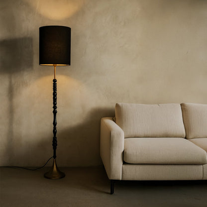 Black floor lamp with fabric shade creating warm ambient lighting beside sofa in a sophisticated living room.
