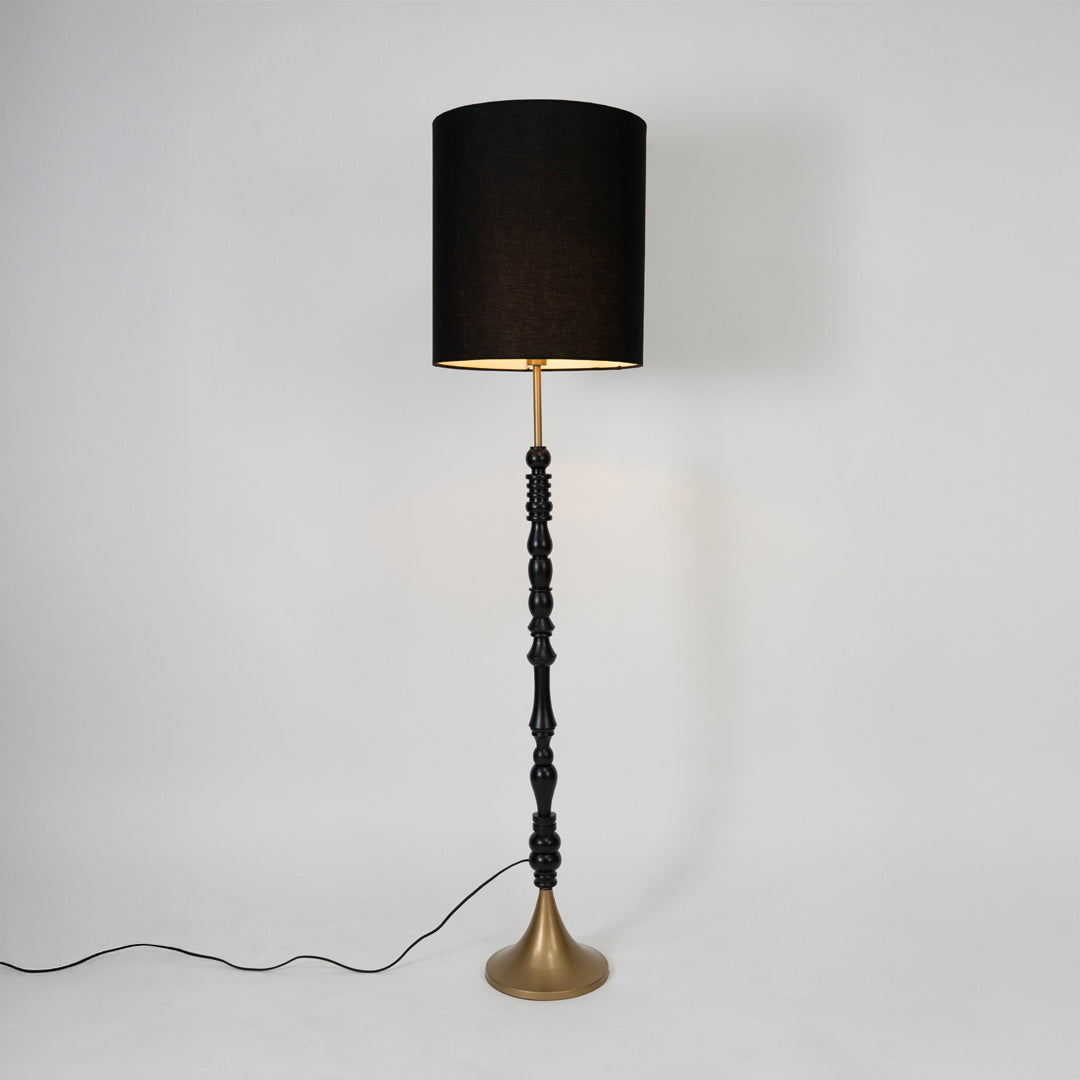 Black fabric shade floor lamp with turned wood stem and brass base designed for elegant living room and bedroom decor.