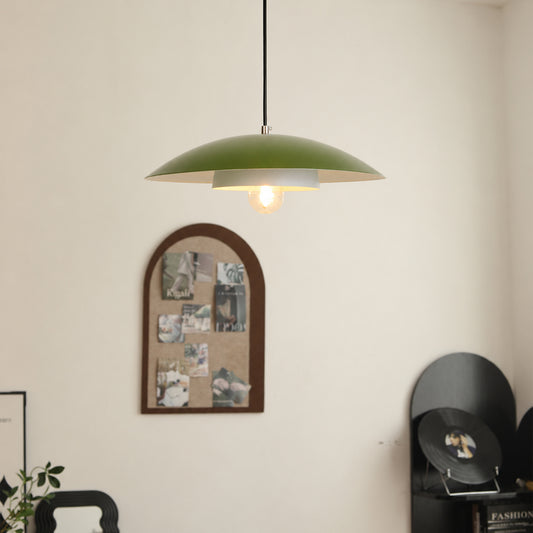 A green dome-shaped pendant light hangs from a black cord in a room with a cream wall, a cork photo collage frame, and a black record player in the background.