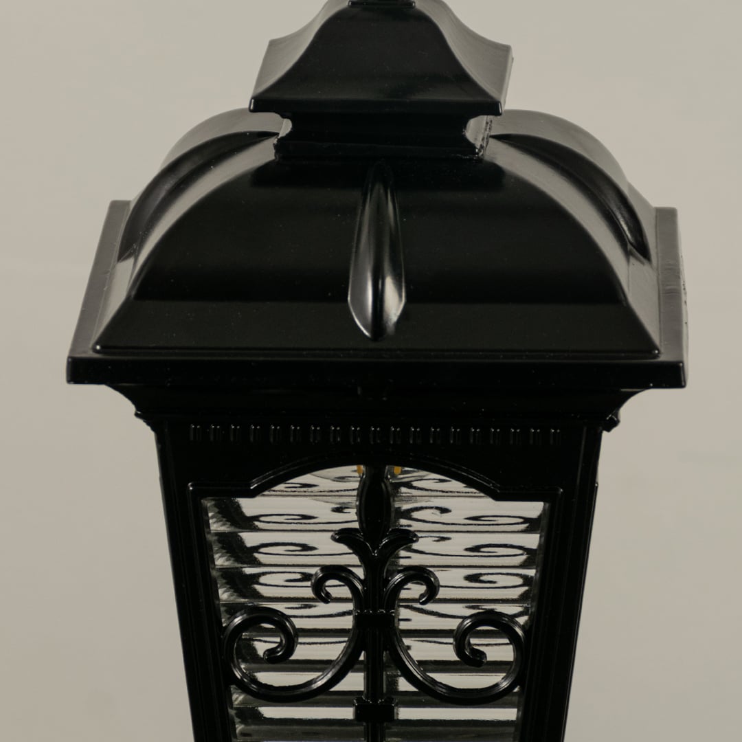 A closeup view of the hanging lantern showing the textured glass and ornate metal detailing with the warm glow inside enhancing the overall aesthetic appeal.