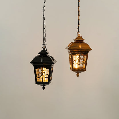 A classic black hanging lantern with the light on displayed against a white background highlighting its ornate design and softly glowing patterned glass panels.