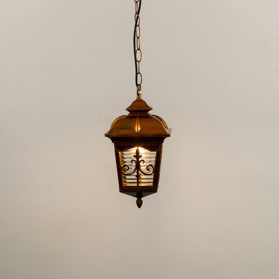 Copper metal hanging outdoor lantern with decorative glass panels glowing on white background ideal for porch entrance and exterior decor lighting.