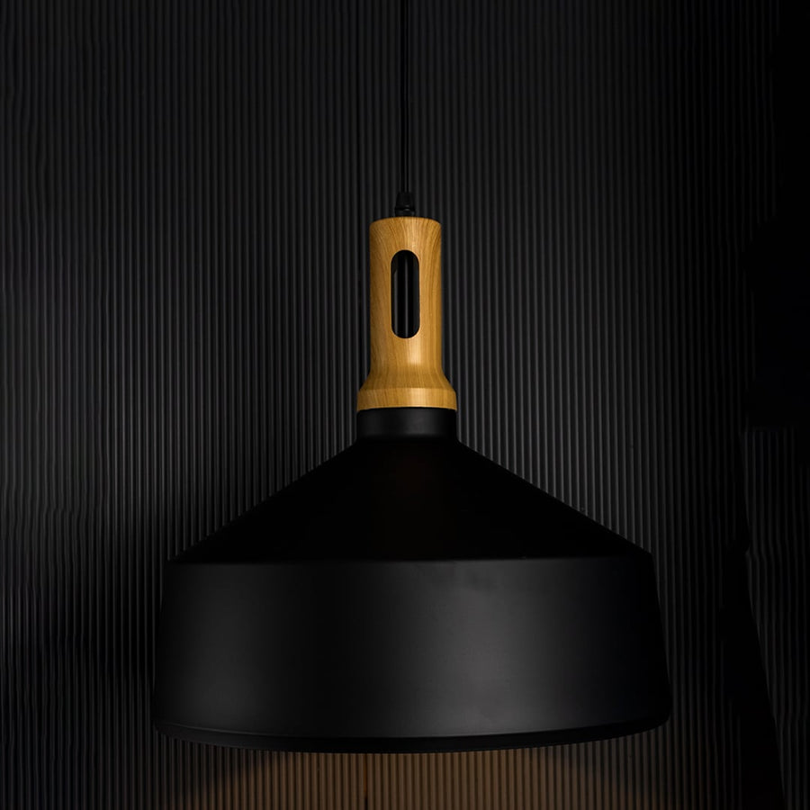 A black pendant light with a wooden top glowing softly against a dark background enhancing its warm light effect and modern sculpted form.