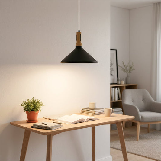 A modern study corner with a black wood pendant light hanging above a wooden desk casting a warm glow across books a plant and a cozy reading area.