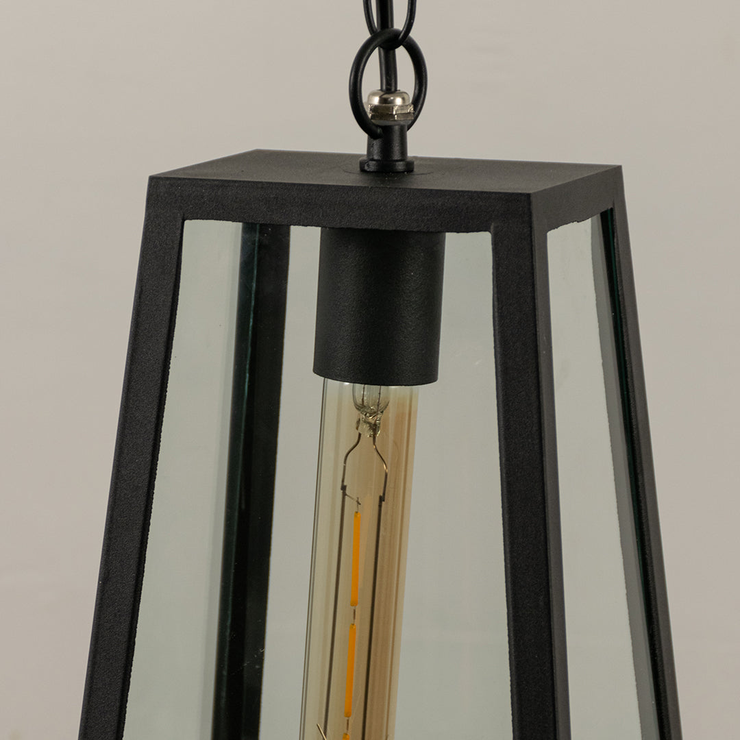 Closeup of black metal hanging outdoor lantern with clear glass panels and bulb on white background perfect for exterior decor lighting.