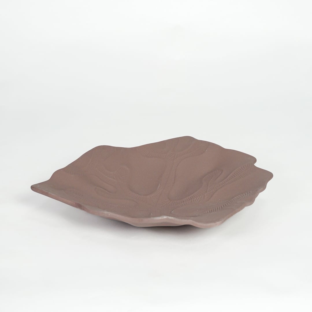 Rustic brown ceramic display platter with sculpted surface and wide design isolated on white background.