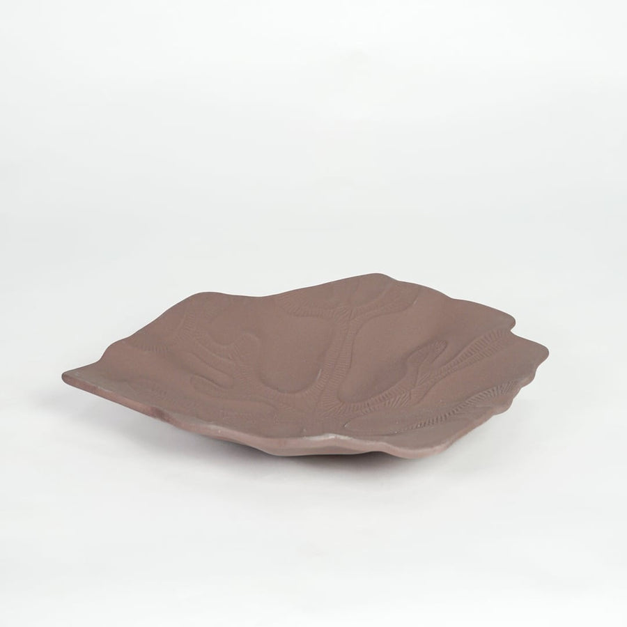 Rustic brown ceramic display platter with sculpted surface and wide design isolated on white background.