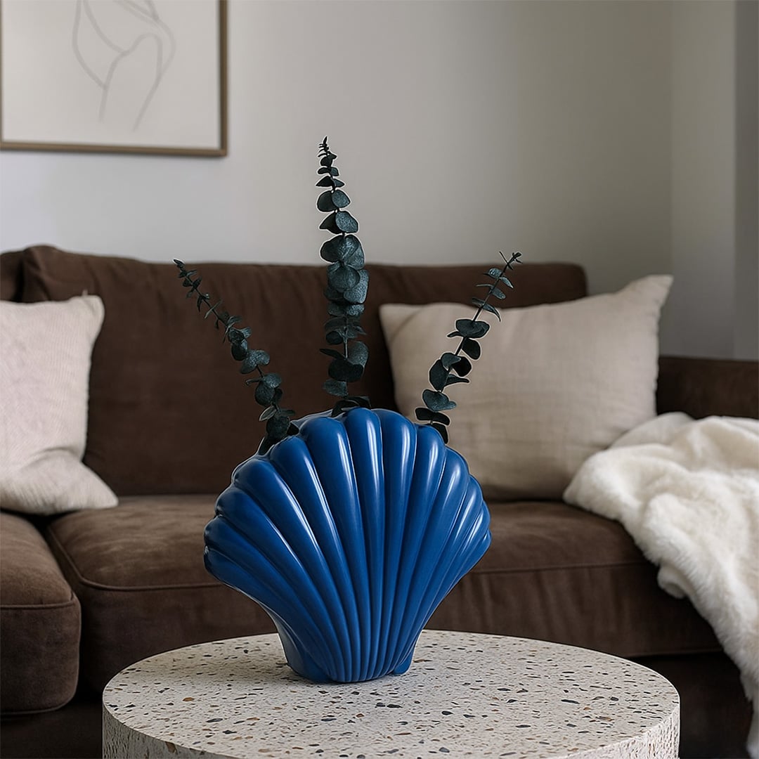 Blue shell shaped ceramic vase styled in a minimal setting adding a coastal decorative touch to modern home interiors.
