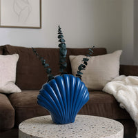 Blue shell shaped ceramic vase styled in a minimal setting adding a coastal decorative touch to modern home interiors.