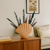 Soft pastel shell shaped vase styled in a clean minimal setting creating a calm decorative look for modern home styling.