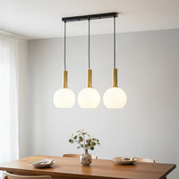 White glass and gold metal pendant lights adding warm elegance above the dining table in interiors.