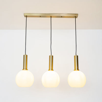 Gold and white glass pendant lights glowing softly on a white background creating warm ambient illumination.