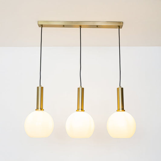 Gold and white glass pendant lights glowing softly on a white background creating warm ambient illumination.