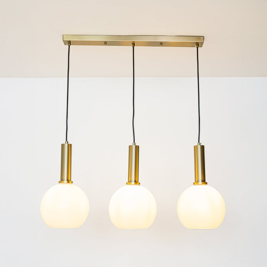 Gold and white glass pendant lights glowing softly on a white background creating warm ambient illumination.