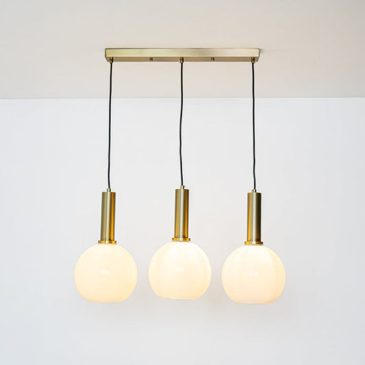 Warm glowing white globe pendant lights with gold holders and adjustable wires displayed against a bright white background for decor styling.
