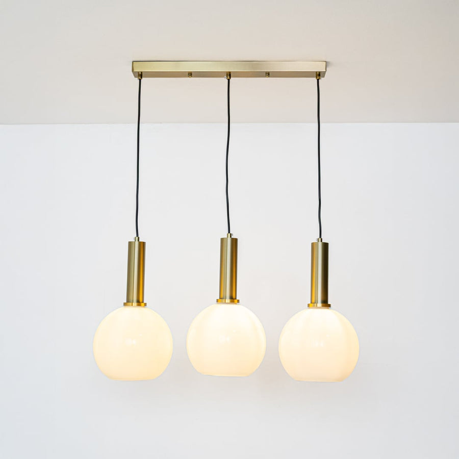 Warm glowing white globe pendant lights with gold holders and adjustable wires displayed against a bright white background for decor styling.
