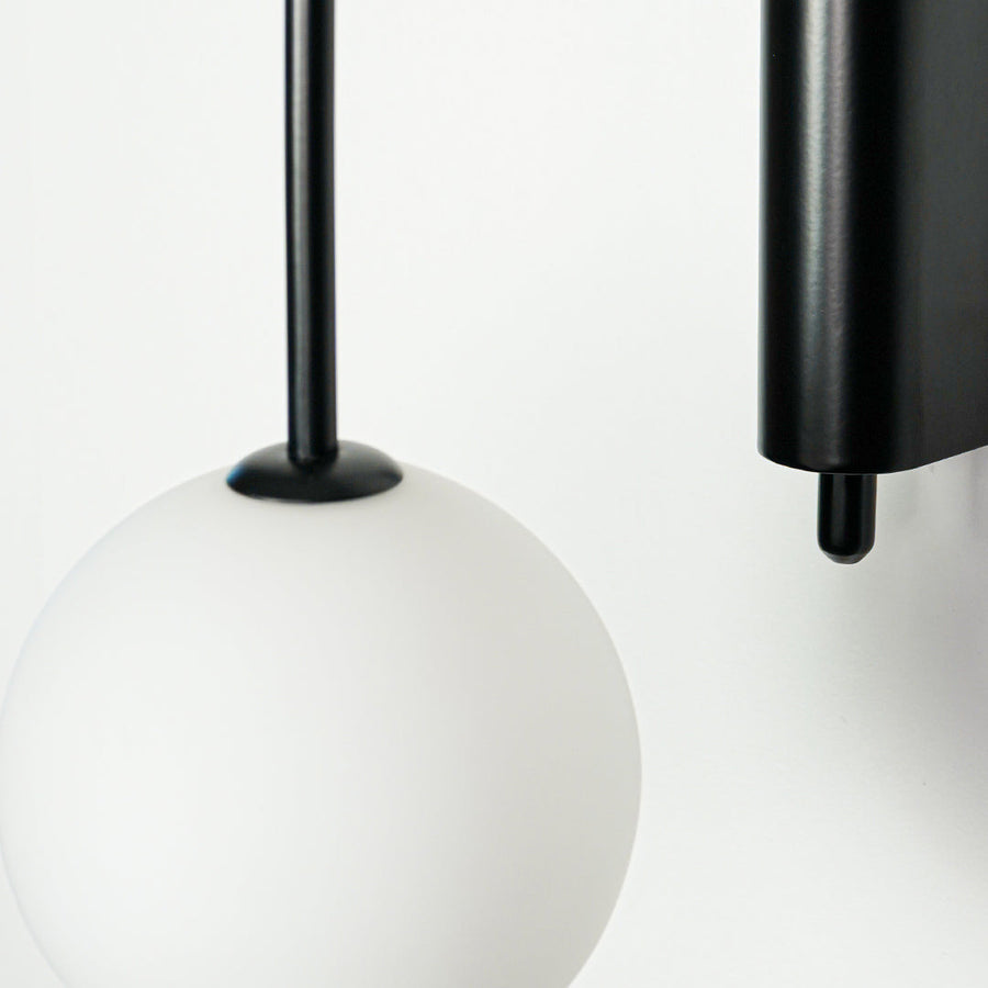 Close view of pendant light with white glass globe and black metal holder on neutral background ideal for modern interior lighting.