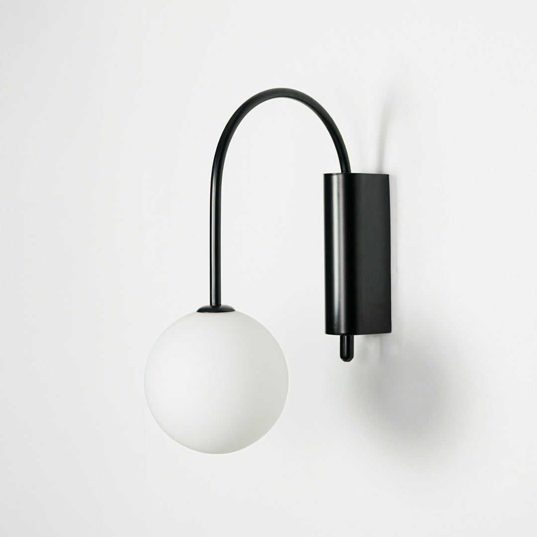 Minimal black wall light with white glass globe shade on clean background perfect for modern home decor lighting.

