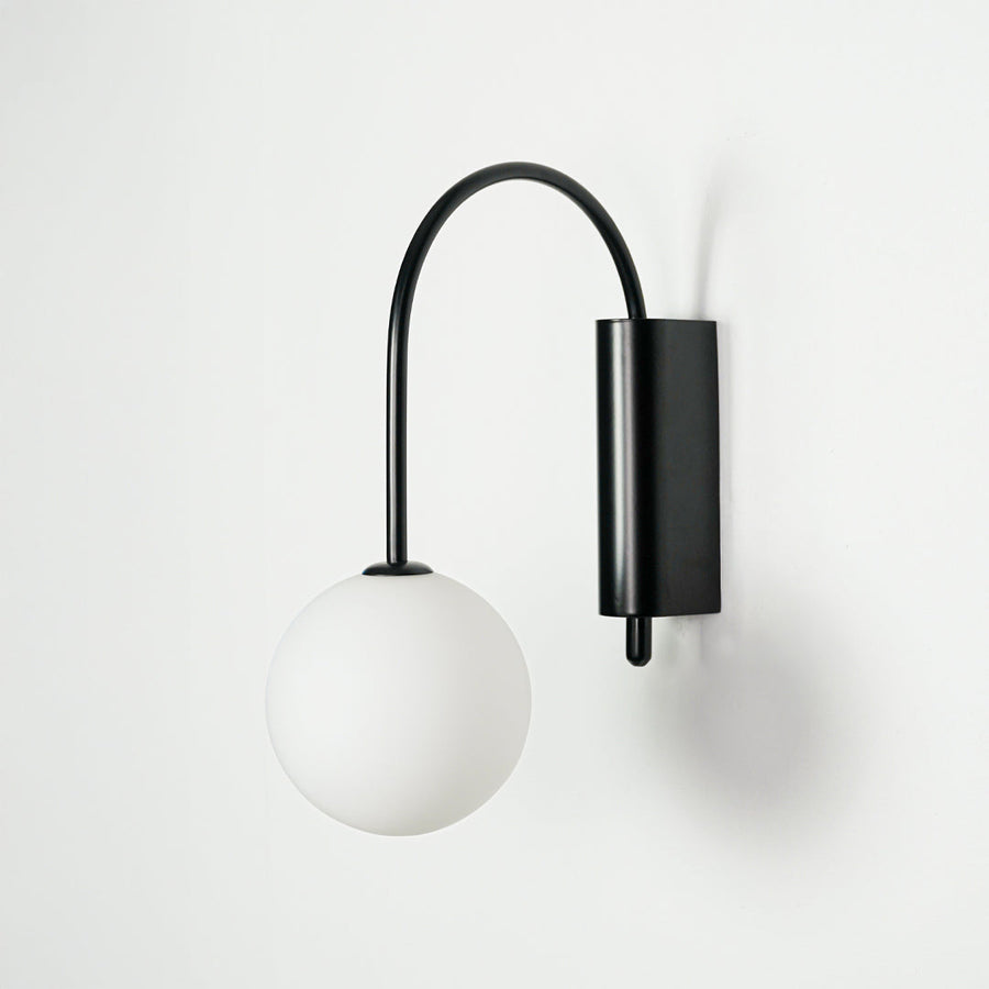 Minimal black wall light with white glass globe shade on clean background perfect for modern home decor lighting.


