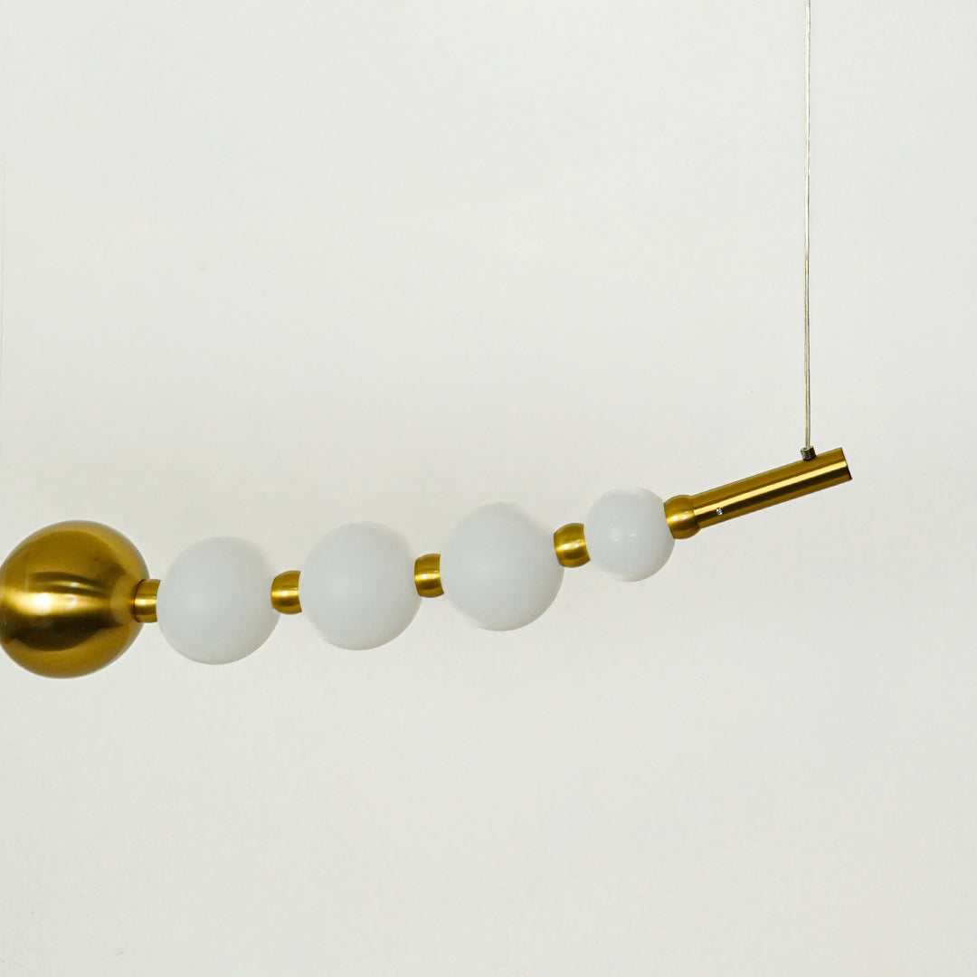 Close view of linear pendant light with frosted glass globes and gold metal rod highlighting premium modern lighting design.