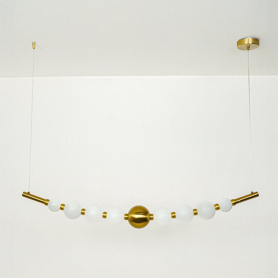 Stylish linear hanging light with multiple white glass globes and gold accents on neutral wall background perfect for modern dining or kitchen lighting.
