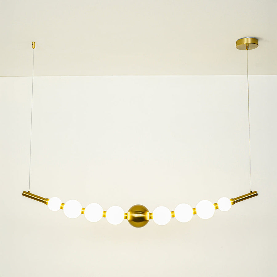 Minimal gold pendant light with white globe shades arranged in linear design on clean neutral background ideal for contemporary home lighting.