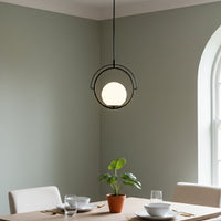 Black metal and white glass ring pendant light adding warm elegance to modern dining interiors.