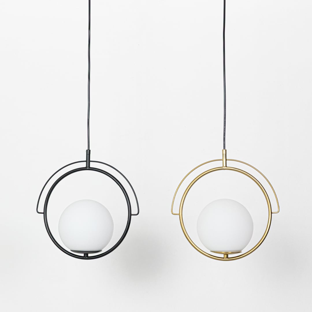 A gold circular pendant pendant light with a white globe shade hanging against a plain background showing the globe unlit and switched off.