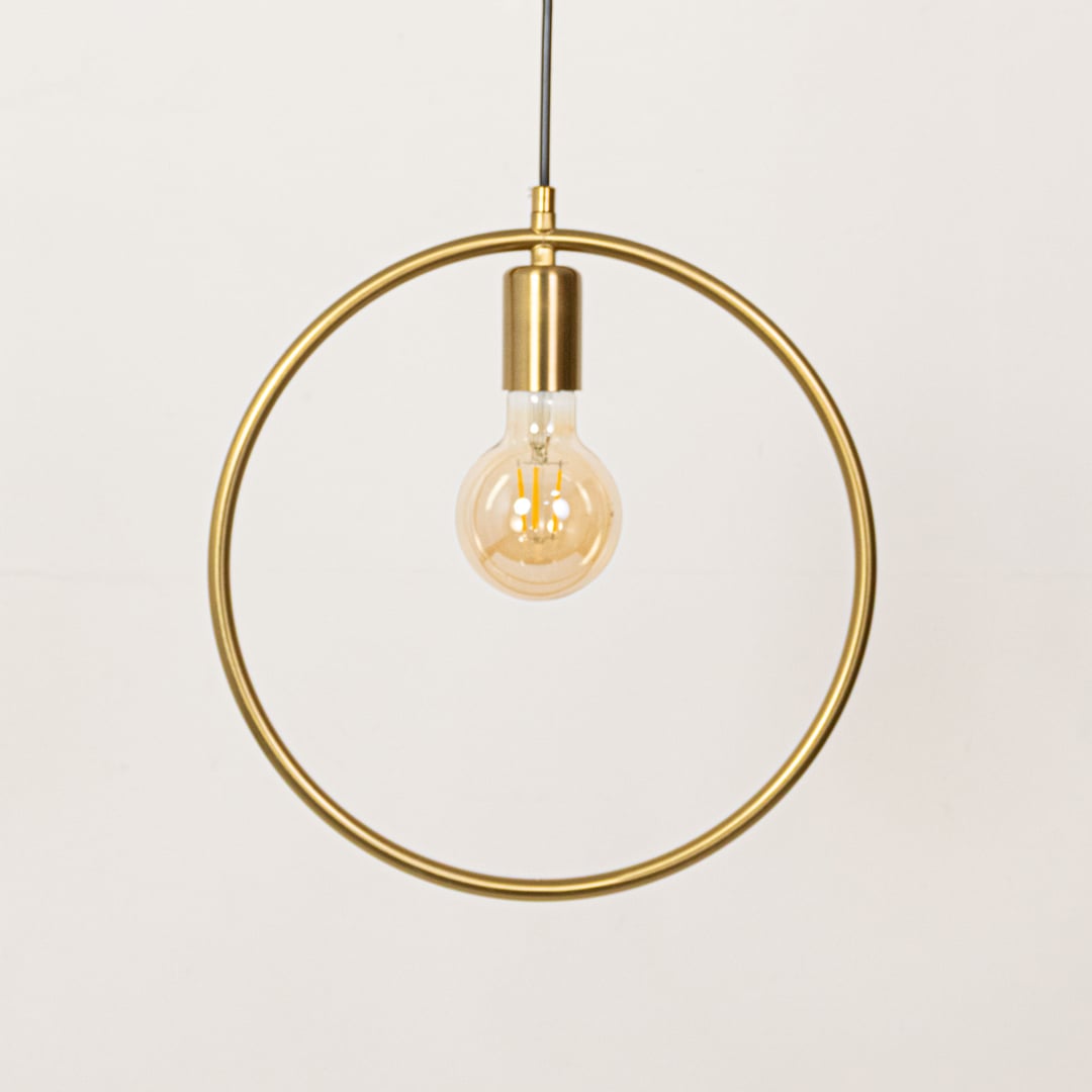 Gold metal ring pendant light with exposed bulb designed for elegant dining room decor spaces.