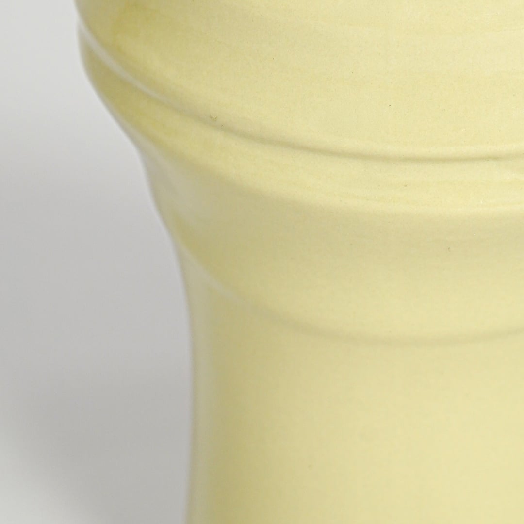 Closeup of yellow ceramic vase showing sculpted rim detail glossy texture and soft pastel finish for home decor styling.
