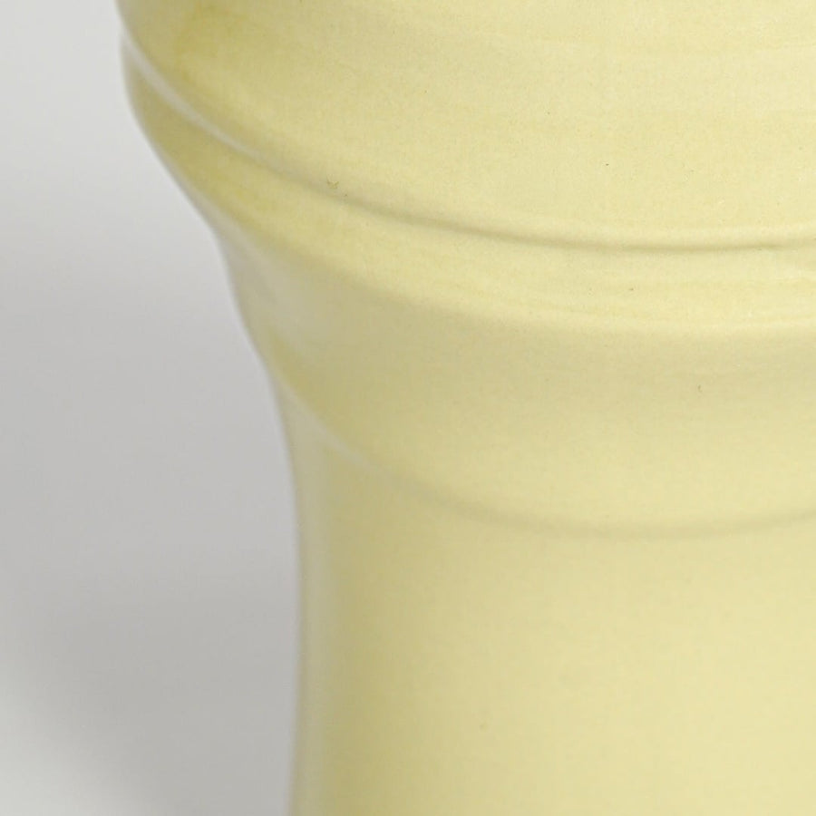Closeup of yellow ceramic vase showing sculpted rim detail glossy texture and soft pastel finish for home decor styling.