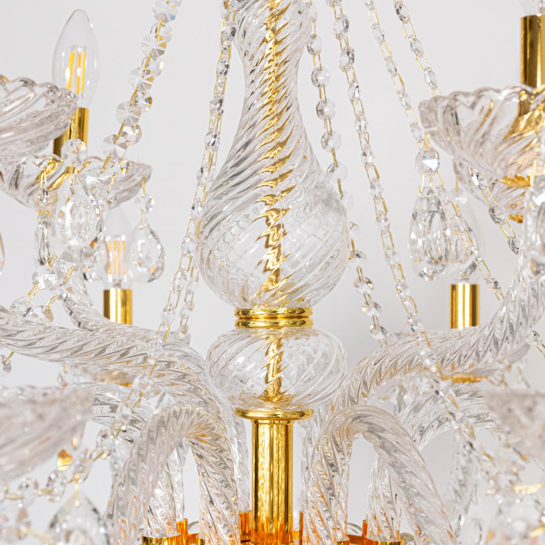 Closeup of chandelier with crystal droplets and gold detailing highlighting elegant luxury decorative light design.