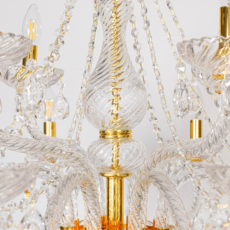 Closeup of chandelier with crystal droplets and gold detailing highlighting elegant luxury decorative light design.