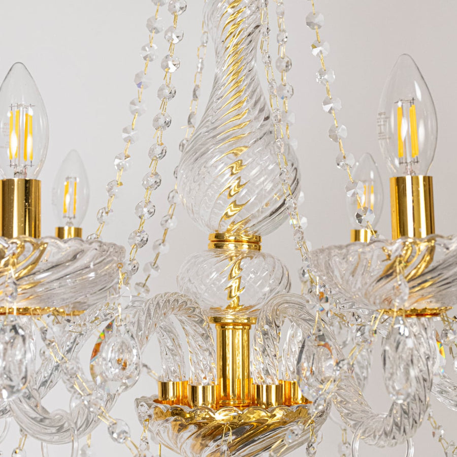 Closeup of chandelier showing crystal arms with gold finish and hanging droplets for stylish luxury design.