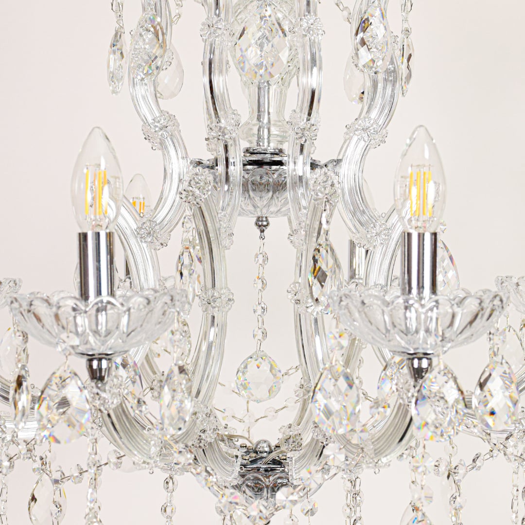 Closeup of crystal glass chandelier arms and drops showing detailed craftsmanship for luxurious home lighting.