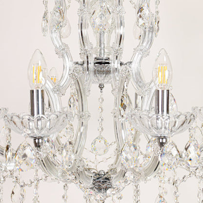 Closeup of crystal glass chandelier arms and drops showing detailed craftsmanship for luxurious home lighting.