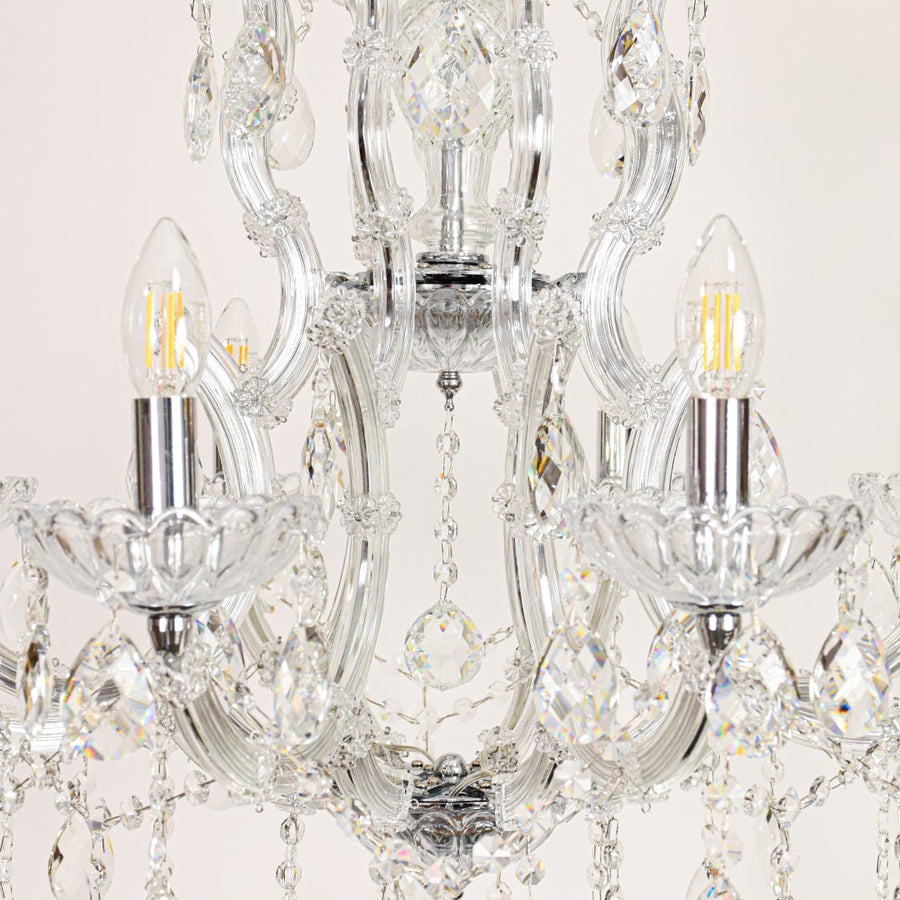 Closeup of crystal glass chandelier arms and drops showing detailed craftsmanship for luxurious home lighting.
