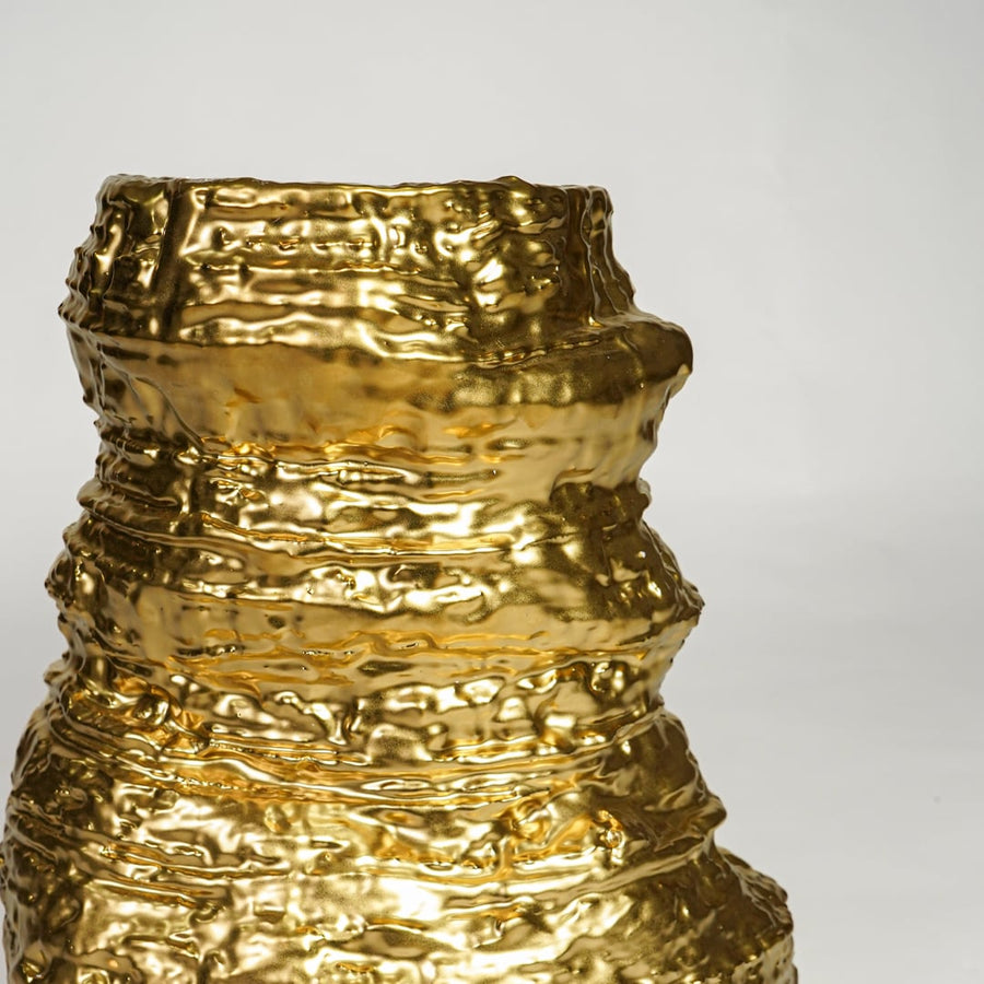 Glossy gold metal designer vase with layered sculptural texture for elegant living room decor display.