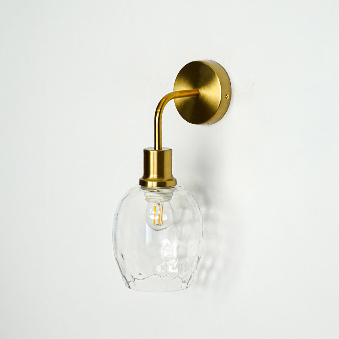 Modern gold metal wall light with textured glass shade for elegant bedroom hallway and living room decor styling.