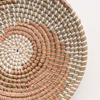 Closeup of handwoven wall basket in natural fiber with pink and white woven detailing for boho wall decor.