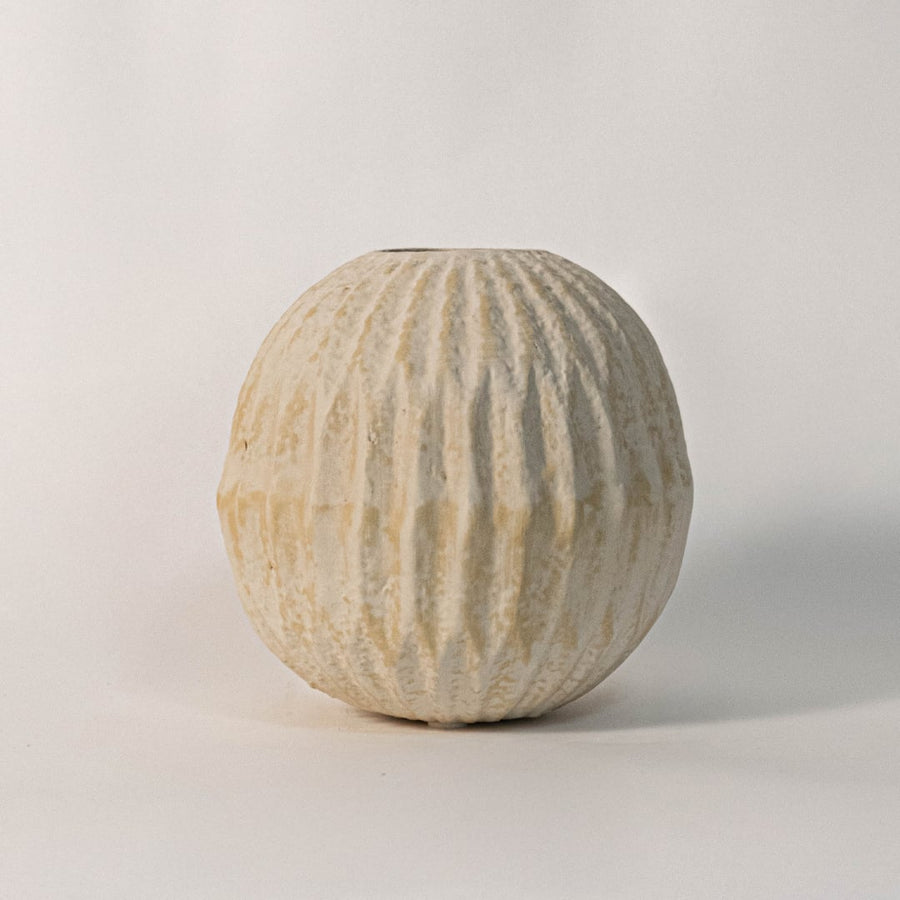 Handcrafted round textured vase photographed on white background highlighting vertical ridges and artisan finish.