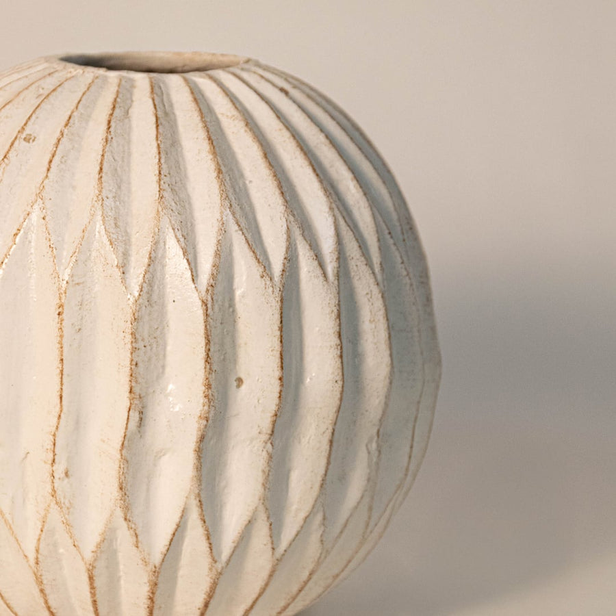 Detailed shot highlighting the carved pattern smooth edges and artisan glaze of the round ceramic vase.